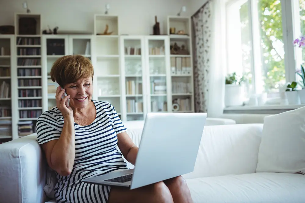 Woman on phone viewing laptop